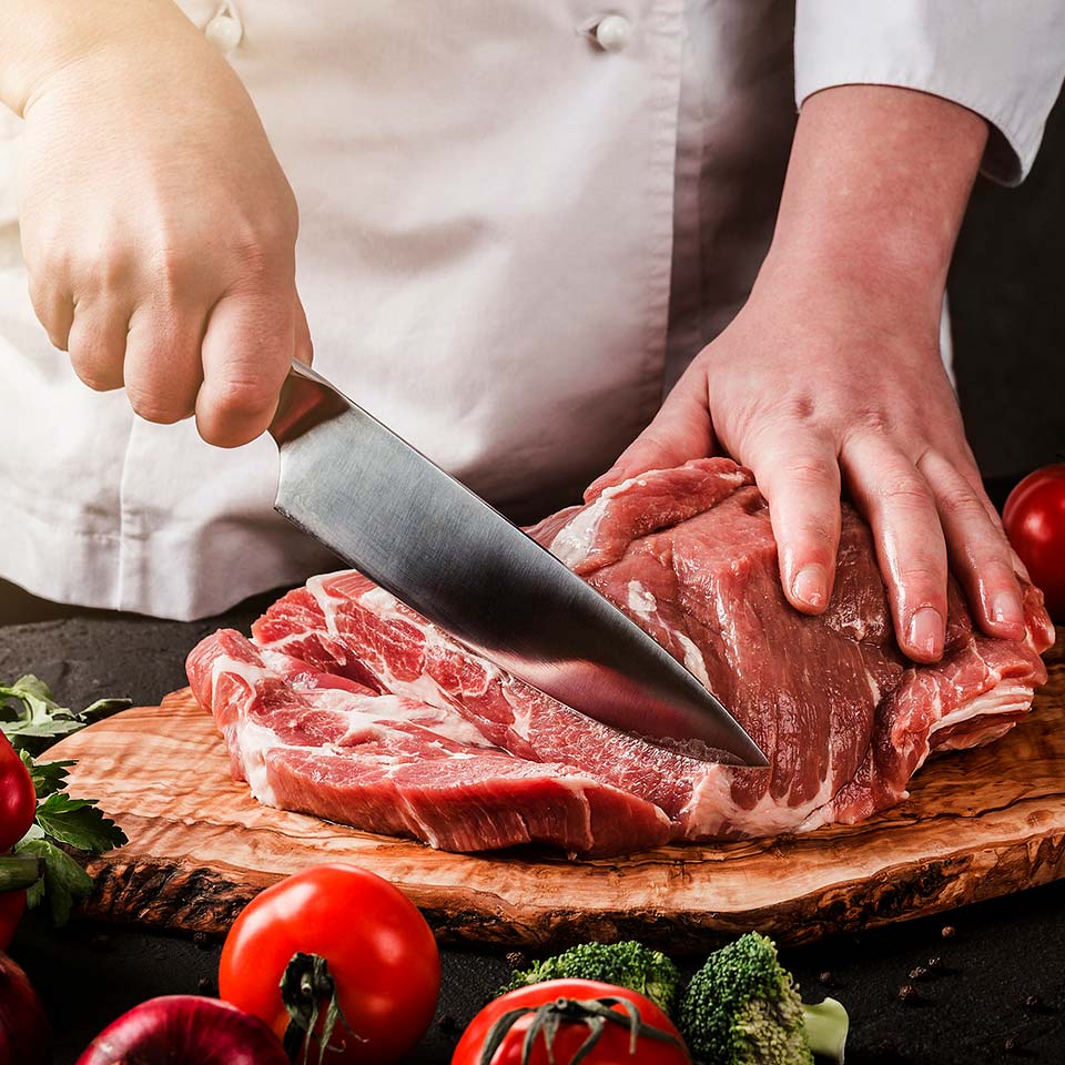 Butcher cuts select pork roast into steaks.