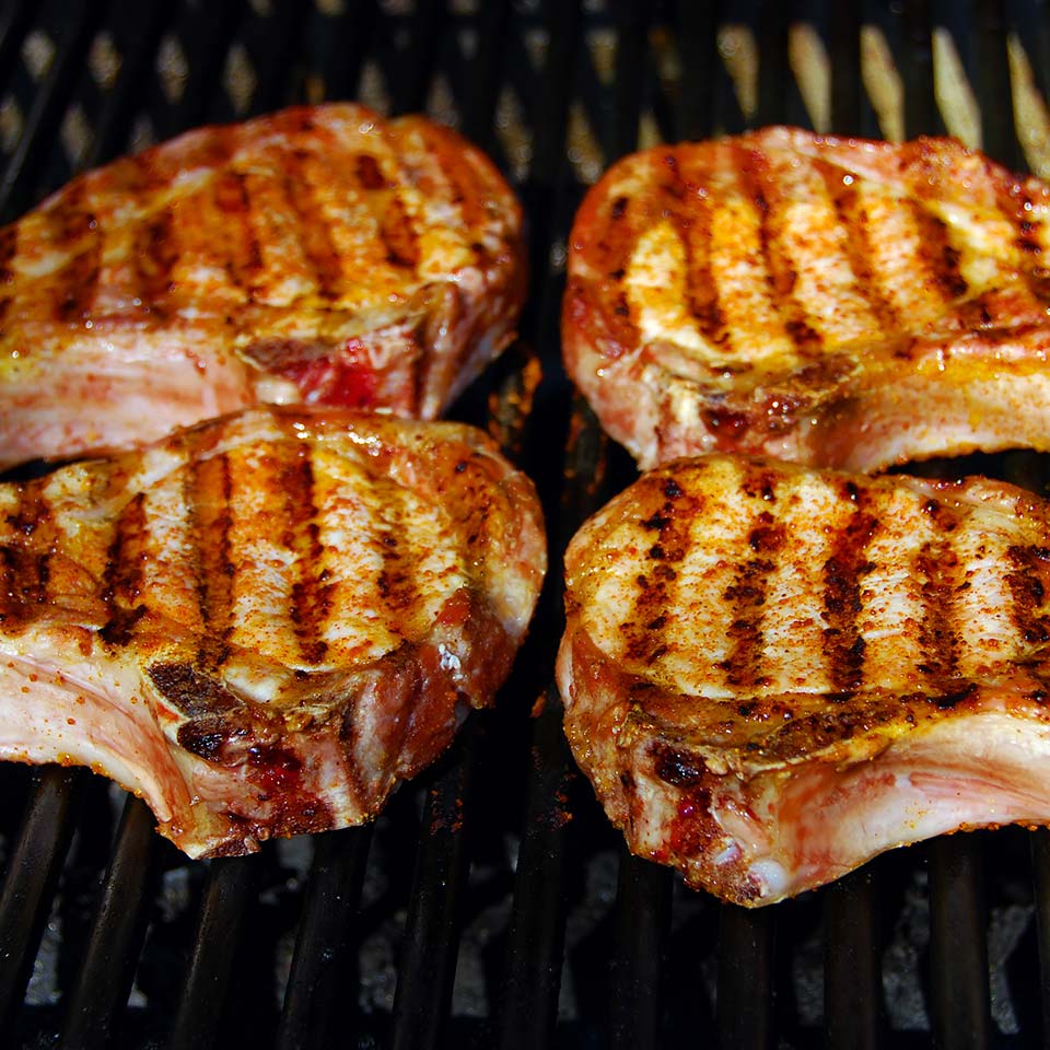 Four pork chops are grilled and seasoned, perfect example of a meat subscription box package.