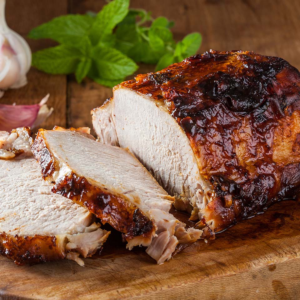 Pork roast sliced and cooked to perfection served on wood cutting board.