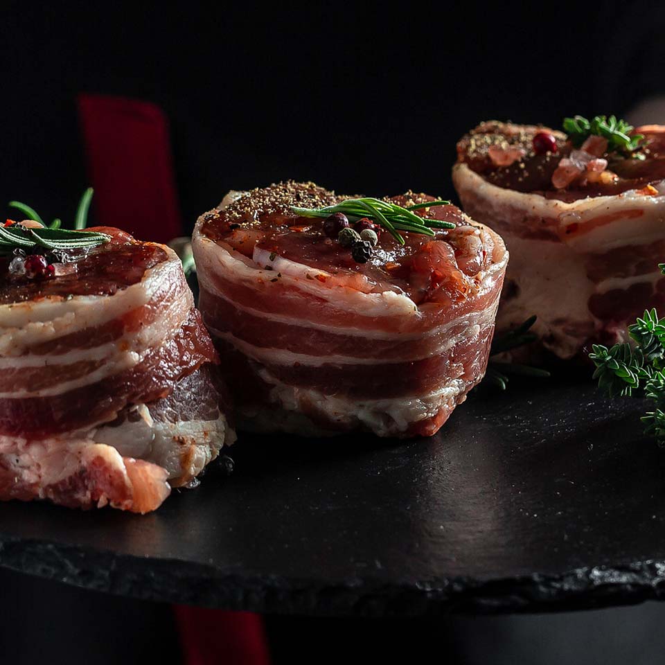 Bacon wrapped filet steaks garnished with whole pepper and rosemary sprigs delivered in Karnovore Krate meat subscription boxes.